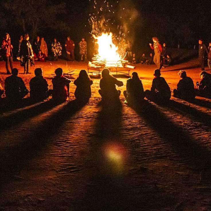 A group of adventure seekers gathered around a warm bonfire under string lights at one of the top stranger camps in Kerala, sharing stories and music.